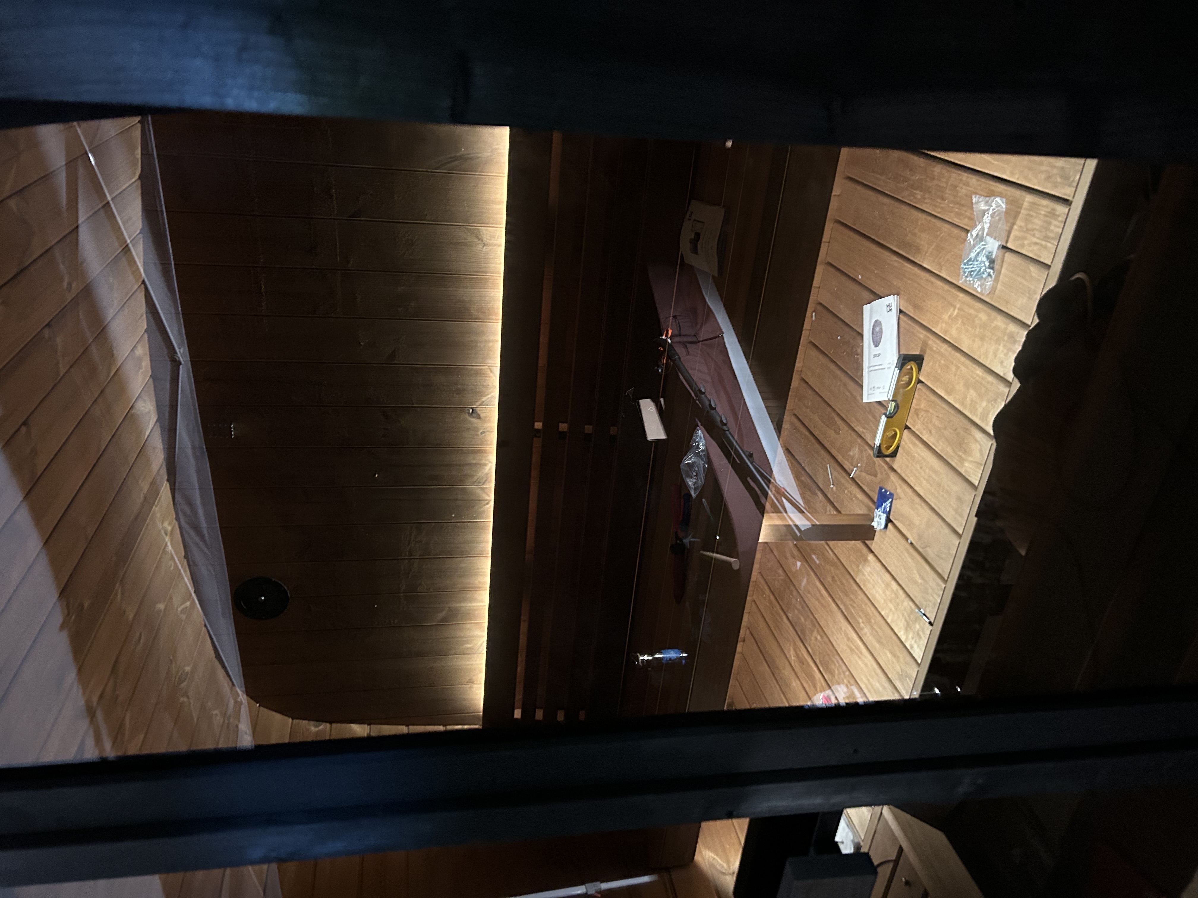 Interior of a wooden sauna during installation with warm LED accent lighting behind the backrest.